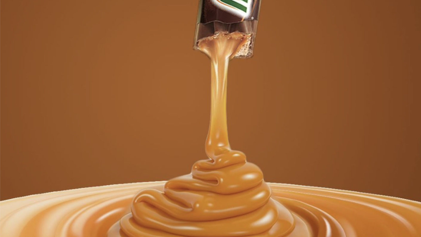 Caramel being poured from an open Milkyway bar into a puddle on brown background