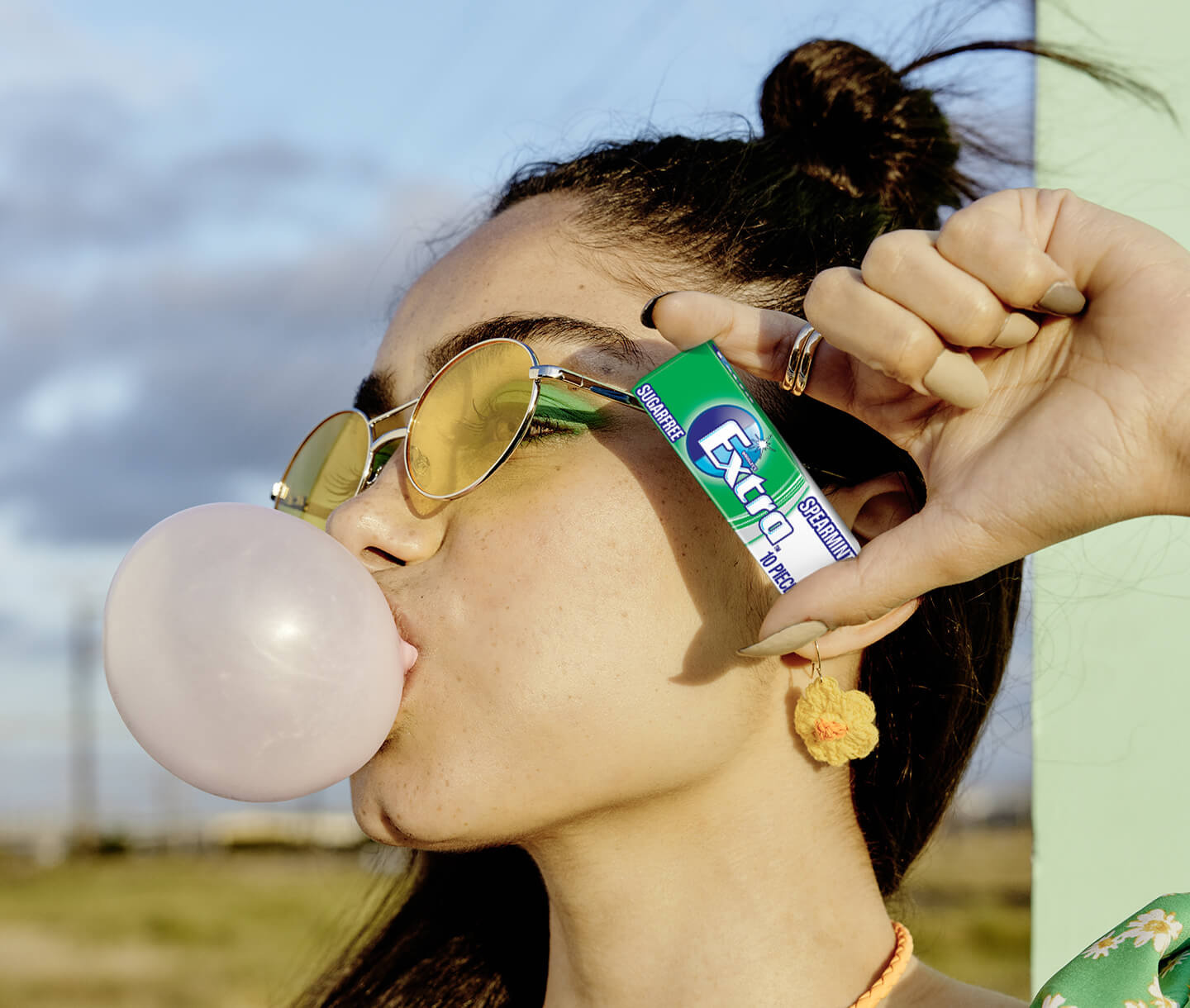 Girl blowing bubble and holding EXTRA packet