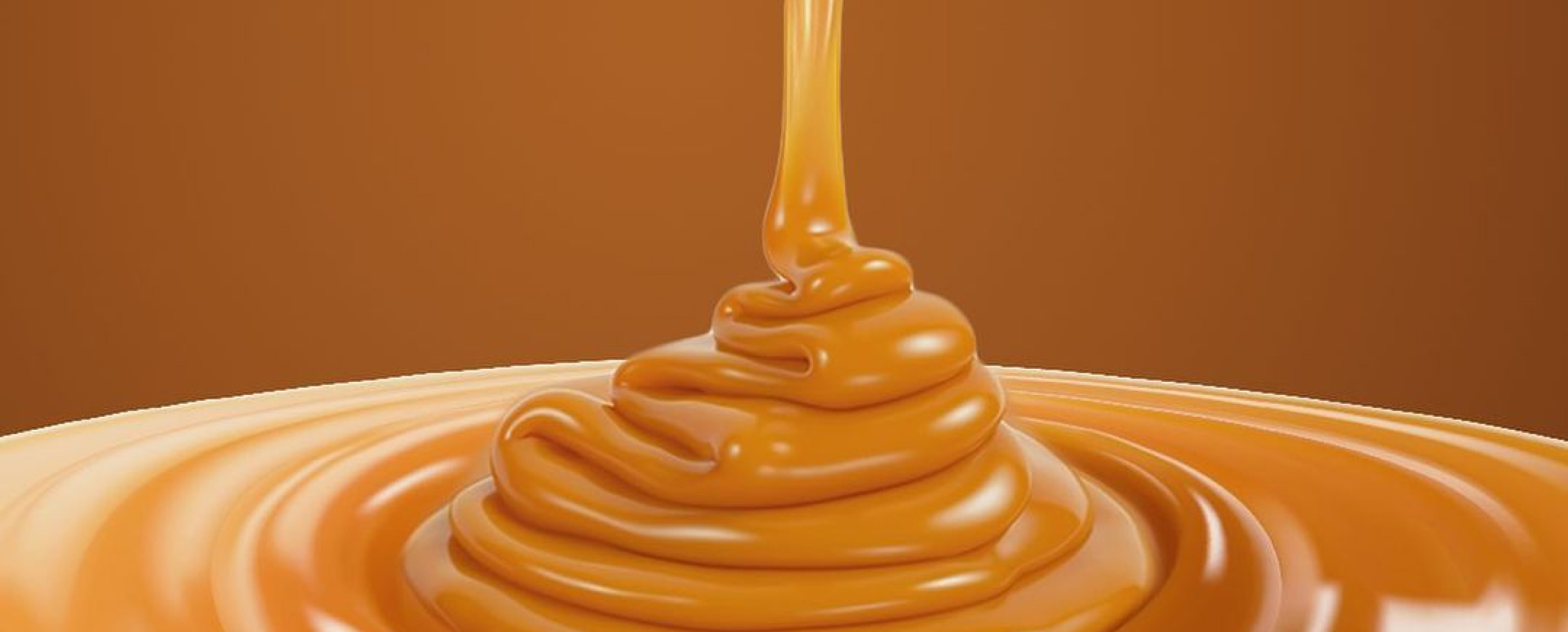Caramel being poured into a puddle on brown background
