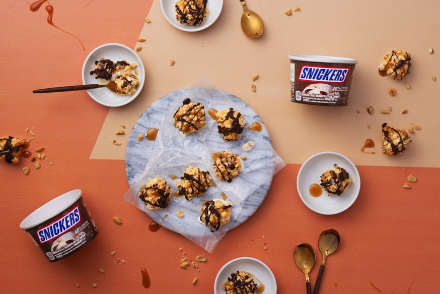 Birds eye view of Snickers Ice cream bites next to Snickers ice cream cups