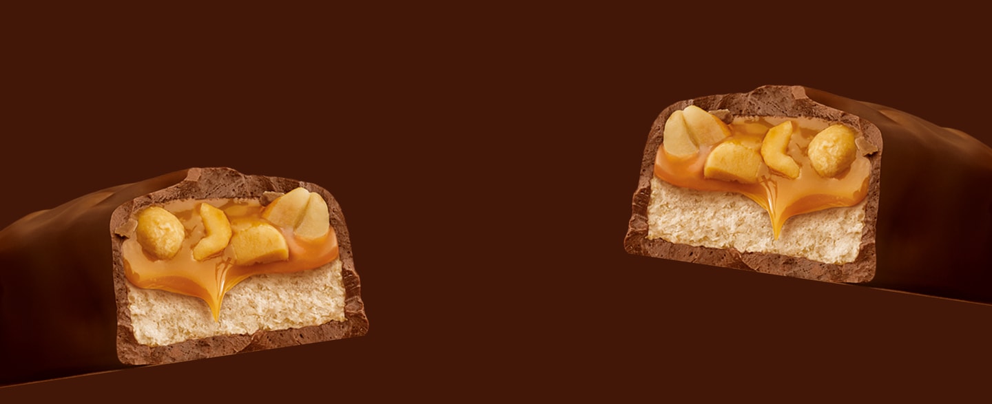 Two cross sections of Snickers classic chocolate bar on brown background