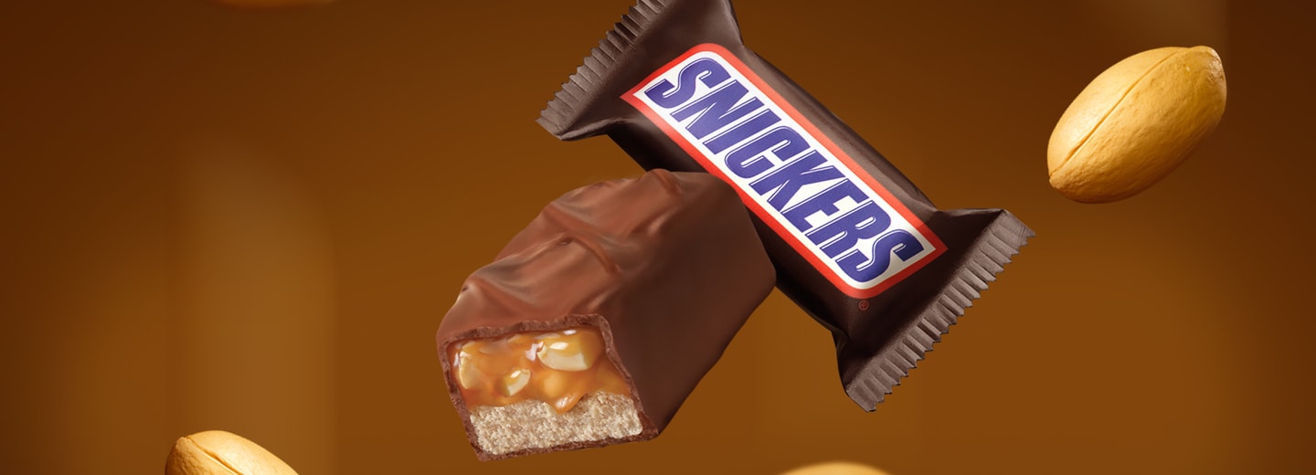 Floating cross-section snickers mini bar, packaged mini bar, and peanuts on brown background
